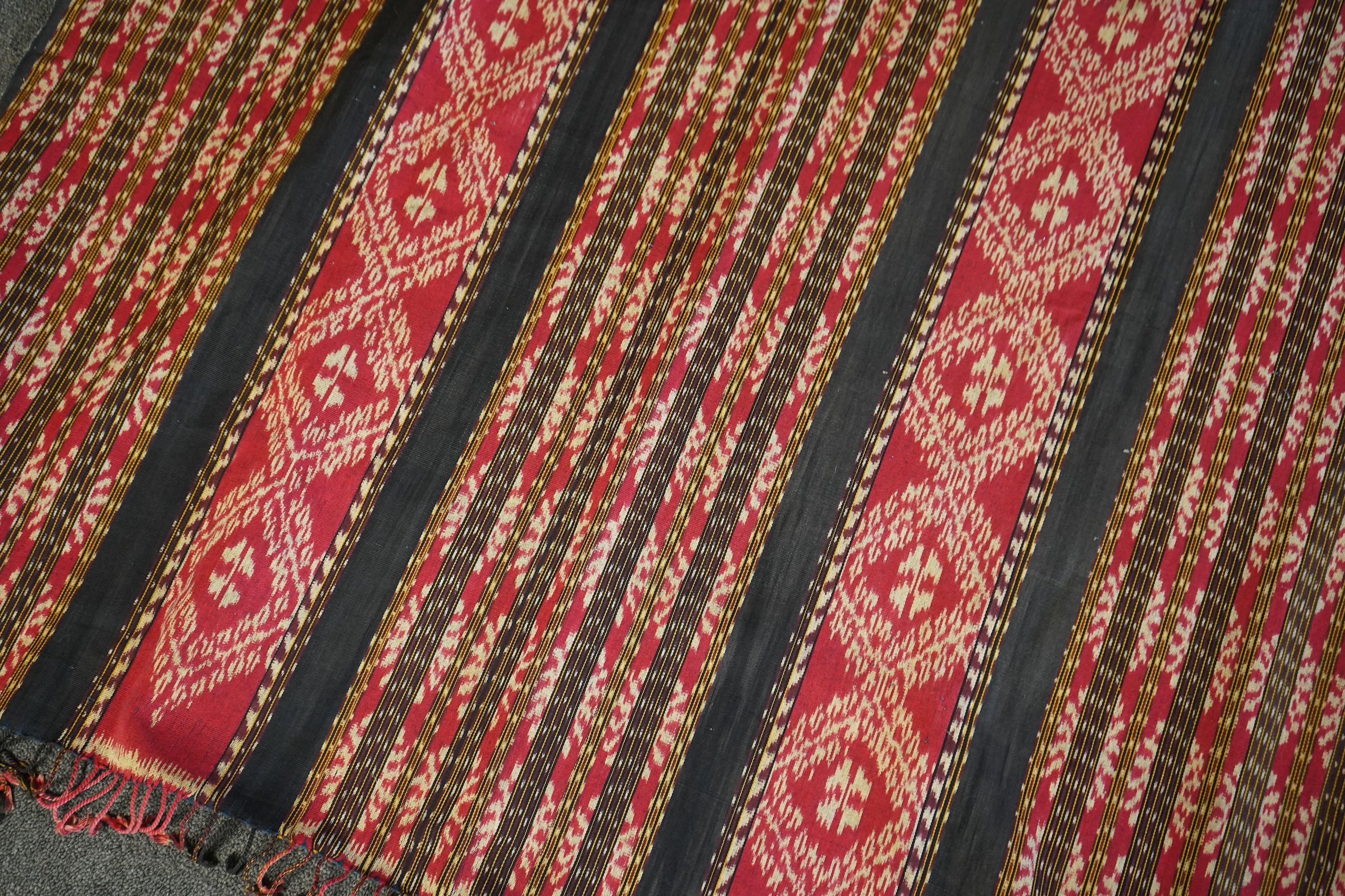 A 20th century Indonesian Sumba single Ikat shoulder cloth, a similar Celebes cloth, a Berber woven skirt and saddle bag and a patchwork cover. (5). Skirt 110cm including hessian top., Condition - some patchwork in the c